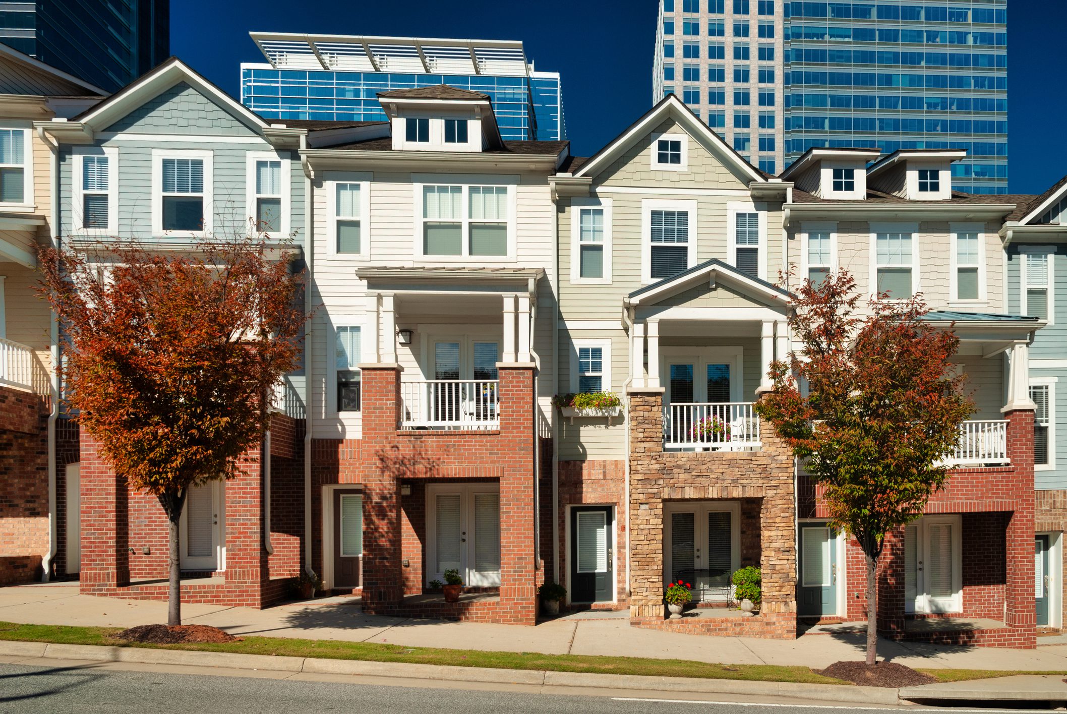 Modern townhouses with autumn trees in front.